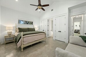 Une chambre à coucher comprenant un lit, des tables de chevet, un ventilateur de plafond et un placard.