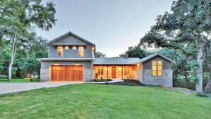 A two-story house with a stone exterior, a large garage, and a well-maintained lawn. - ⭐️⭐️LUXURY WATERFRONT-CHEF’S KITCHEN-FIRE PIT-SLEEPS 24⭐️⭐️ (Horseshoe Bay)