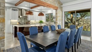 A modern kitchen with a stone accent wall, wooden beams, pendant lighting, and a large island. - ⭐️⭐️LUXURY WATERFRONT-CHEF’S KITCHEN-FIRE PIT-SLEEPS 24⭐️⭐️ (Horseshoe Bay)