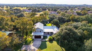 Une grande maison avec un garage, entourée d’arbres et d’une pelouse bien entretenue.