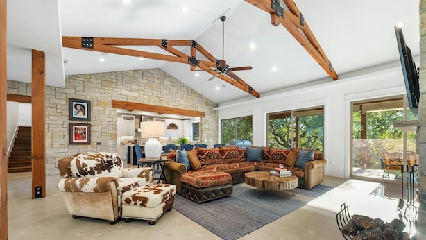A spacious living room with a stone fireplace, a large sectional sofa, and a ceiling fan. - ⭐️⭐️LUXURY WATERFRONT-CHEF’S KITCHEN-FIRE PIT-SLEEPS 24⭐️⭐️ (Horseshoe Bay)