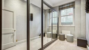 Moderni hotellihuone, jossa on suuri liukuovi, suuri ikkuna ja pieni oleskelualue, jossa on nojatuoleja.