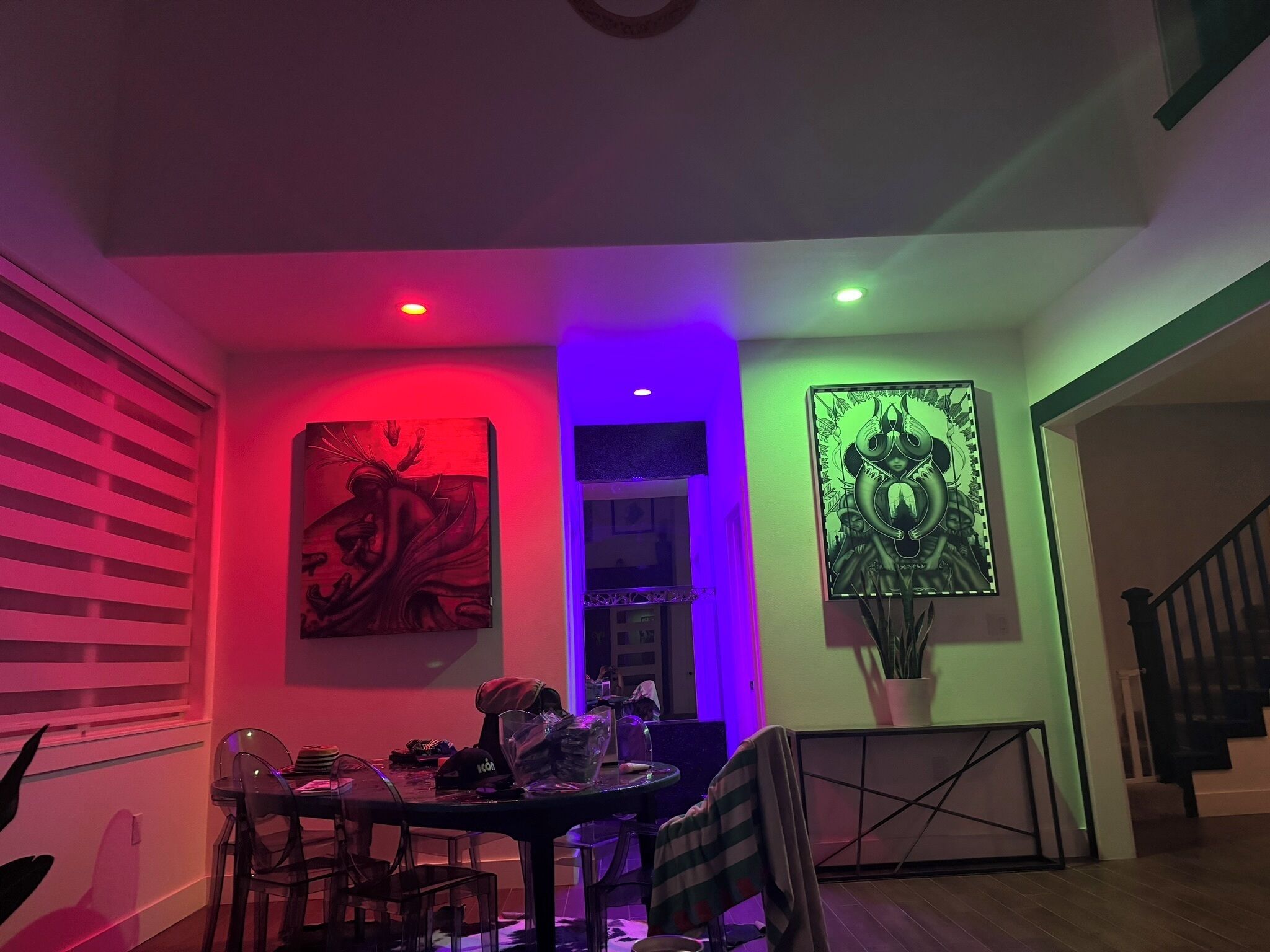 A dining area with a table and chairs, two artworks on the walls, and a staircase to the right.