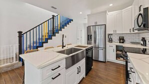 Une cuisine moderne avec des meubles blancs, des appareils en acier inoxydable et un plancher en bois.