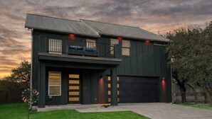 Une maison moderne à deux étages, dotée d’un garage, d’un balcon et d’une pelouse bien entretenue.
