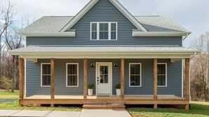 A two-story house with a front porch, a central door, and a small front yard. - Sleeps 20 | Family-friendly | Near DT LYH & LU (Madison Heights)