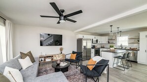 A modern living room with a sofa, chairs, a coffee table, and a TV. - Sleeps 20 | Family-friendly | Near DT LYH & LU (Madison Heights)