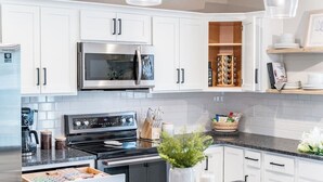 A modern kitchen with white cabinets, stainless steel appliances, and a granite countertop. - Sleeps 20 | Family-friendly | Near DT LYH & LU (Madison Heights)