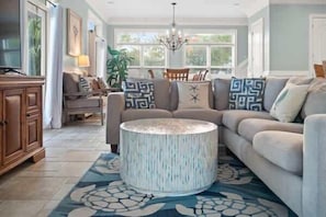 A living room with a round coffee table, a sofa, and a cabinet. - Reel Time  6 BD St George Island, FL Vacation Re (St. George Island)
