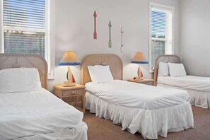 A hotel room with two single beds, a nightstand with a lamp, and a window with blinds. - Reel Time  6 BD St George Island, FL Vacation Re (St. George Island)