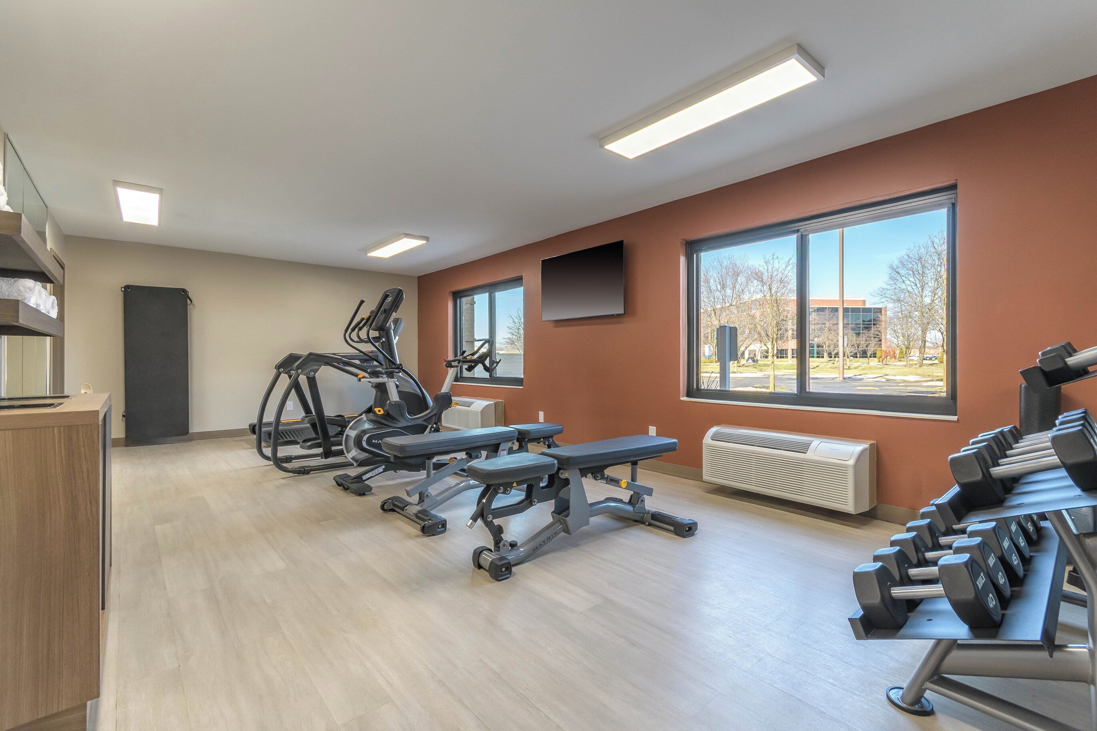 A gym with treadmills, benches, and dumbbells.