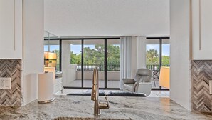 A modern kitchen with a large window, a marble countertop, and a view of the outdoors. - Across Street to Main Beach Access, Tennis, Heated Pool (Siesta Key)