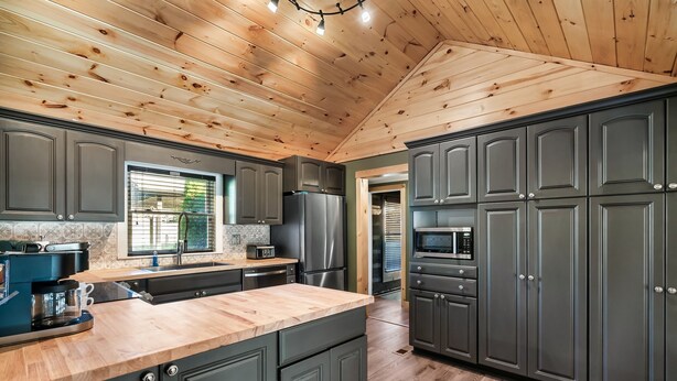 A modern kitchen with dark cabinets, a wooden ceiling, and a large island. - River Access! Kayak/ Fire pit/ Hot Tub/ Top 10% (Sevierville)