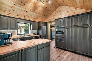 A modern kitchen with dark cabinets, a wooden ceiling, and a large island.