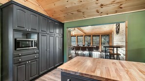 A modern kitchen with dark cabinets, a microwave, and a wooden countertop. - River Access! Kayak/ Fire pit/ Hot Tub/ Top 10% (Sevierville)