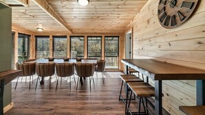 A wooden interior with a large clock, a long dining table, and multiple chairs. - River Access! Kayak/ Fire pit/ Hot Tub/ Top 10% (Sevierville)
