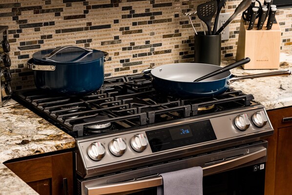 A kitchen with a gas stove, a blue pot, and a frying pan on the counter. - Stay In Evergreen - Denver Mountain Escape (Evergreen)