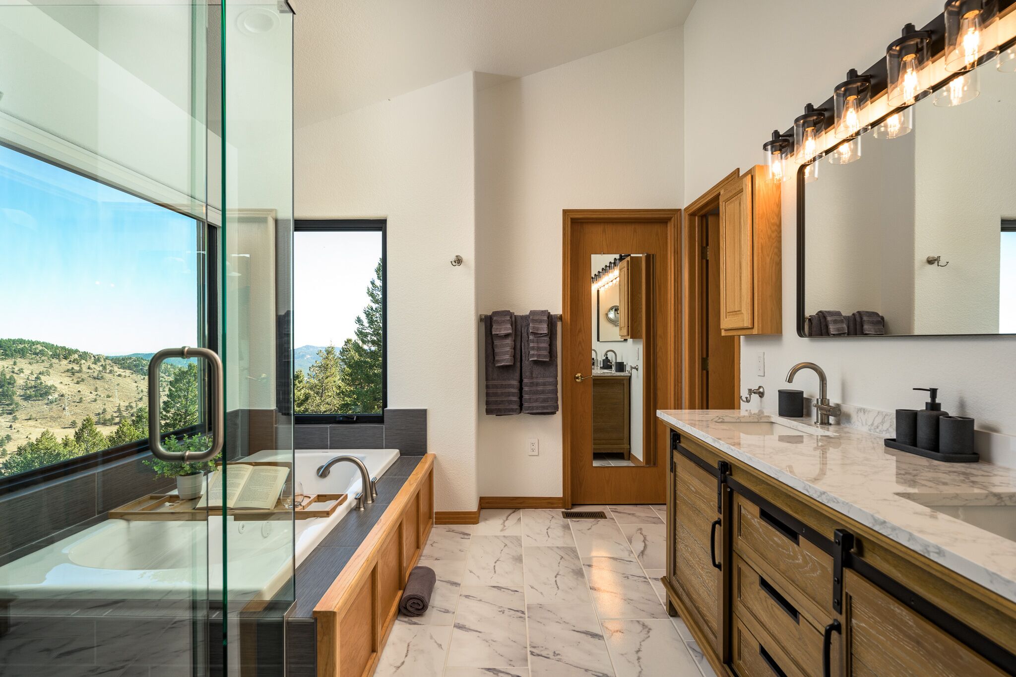 Une salle de bain moderne dotée d’une douche à parois de verre, d’un grand miroir et d’un meuble-lavabo avec un évier et un plan de travail.