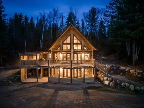 Une cabane en bois à deux étages, dotée d’un balcon et entourée d’arbres.