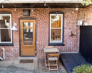 A brick building with a wooden door, two windows, a small table, and a bench. - Elegant townhome with a Hot Tub for couples and small families - Lancaster City  (Lancaster)