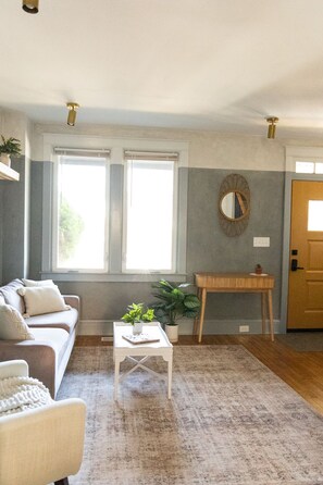 A living room with a sofa, a coffee table, a small table with a plant, and a mirror on the wall. - Elegant townhome with a Hot Tub for couples and small families - Lancaster City  (Lancaster)