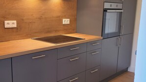 Uma cozinha moderna com bancada de madeira, armários cinza e forno embutido.
