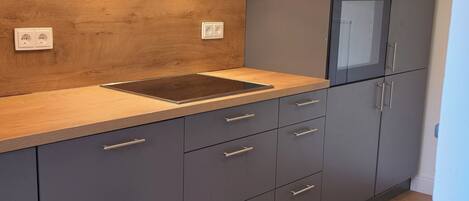 A modern kitchen with a wooden countertop, grey cabinets, and a built-in oven.
