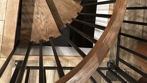 A spiral staircase with wooden steps and black metal railings. - Kick back and relaxing luxury home, calm western space near the Broadmoor. (Colorado Springs)