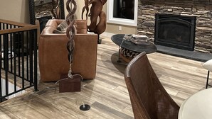 A modern living room with a fireplace, a ceiling fan, a large mirror, and a television. - Kick back and relaxing luxury home, calm western space near the Broadmoor. (Colorado Springs)