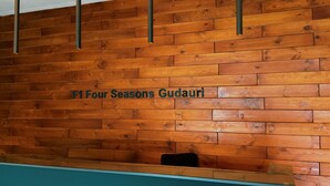 A reception desk with a wooden panel wall and a sign that reads "F1 Four Seasons Gudauri." - Gudauri Ski Resort - Four Seasons (Kazbegi)