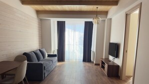 A modern living room with a sofa, dining table, and TV. - Gudauri Ski Resort - Four Seasons (Kazbegi)