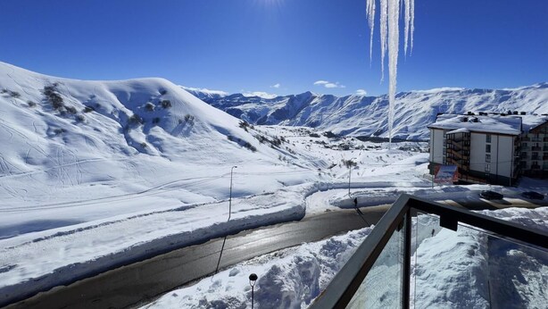 A snow-covered landscape with a clear sky, a road, and a building with multiple floors. - Gudauri Ski Resort - Four Seasons (Kazbegi)