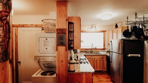 A compact kitchen with wooden cabinets, a built-in stove, a sink, and a refrigerator. - Relax in "Big Sky" Style just 3 blocks from the Symes Mineral Soaks! (Hot Springs)