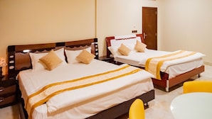 Habitación de hotel con dos camas, una mesita y sillas amarillas.