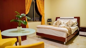 Una habitación de hotel con una cama, una mesita redonda y sillas amarillas.