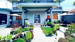Un hotel con entrada principal, terraza al aire libre y un jardín cuidado.