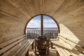 Un pontile in legno con una griglia e panche, con vista su uno specchio d'acqua e una costa lontana.