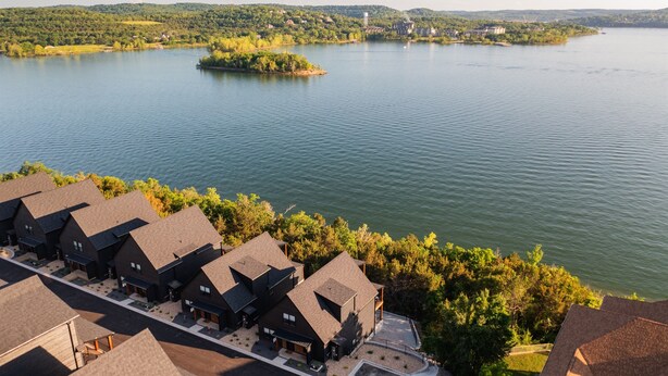 A lakeside residential area with multiple houses, a clear view of the lake, and a small island in the distance.
