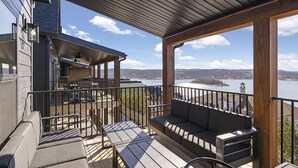A covered outdoor seating area with a view of a lake and distant buildings.