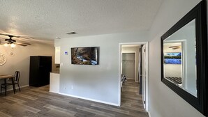 A modern interior with a dining area, a kitchen, and a hallway leading to a bathroom. - Piney Woods 6 - King Bed (Texarkana)