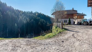 A rural setting with a dirt road, a wooden house, and a tractor. - Farmhouse 'Innerjerberhof Sunnseit' with Mountain View, Shared Terrace and Wi-Fi (Laurein)