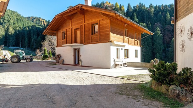 A wooden cabin with a large porch, a dirt driveway, and a tractor in the background. - Farmhouse 'Innerjerberhof Sunnseit' with Mountain View, Shared Terrace and Wi-Fi (Laurein)