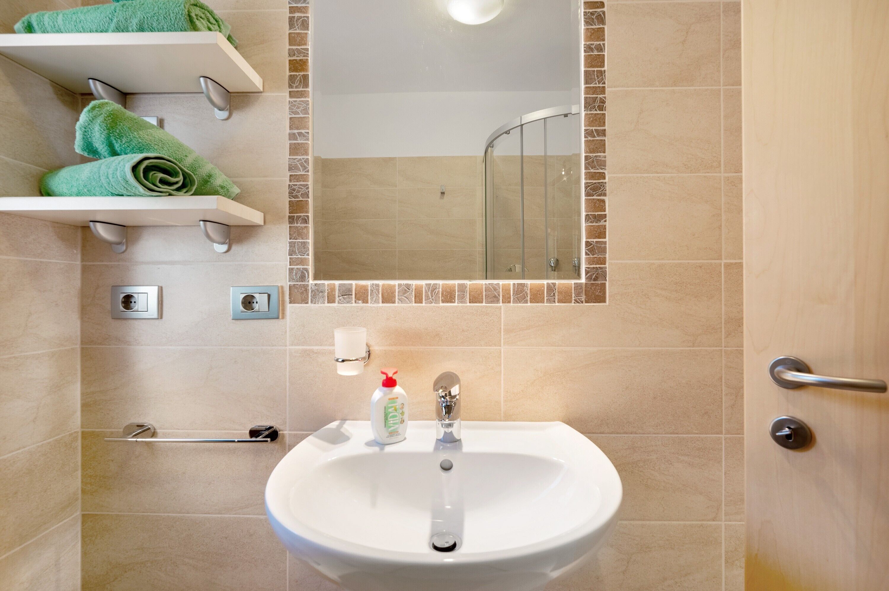 A bathroom with a sink, mirror, towel rack, and shower.