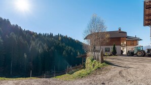A rural setting with a dirt road, a wooden house, and a tractor. - Farmhouse 'Innerjerberhof Neiderseit' with Mountain View, Shared Terrace and Wi-Fi (Laurein)