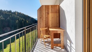 A wooden balcony with a table and chair, overlooking a forested valley. - Farmhouse 'Innerjerberhof Neiderseit' with Mountain View, Shared Terrace and Wi-Fi (Laurein)