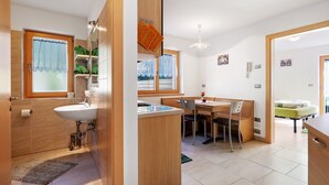 A compact kitchen with a sink, a dining table with chairs, a small window, and a door leading to another room. - Farmhouse 'Innerjerberhof Neiderseit' with Mountain View, Shared Terrace and Wi-Fi (Laurein)