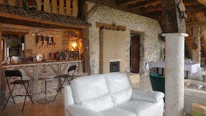 A rustic interior with a stone wall, a white leather sofa, a bar area with bottles, and a wooden ceiling. - Country House "Domaine Baraque" with Mountain View, Wi-Fi, and Air Conditioning (Pouillon)