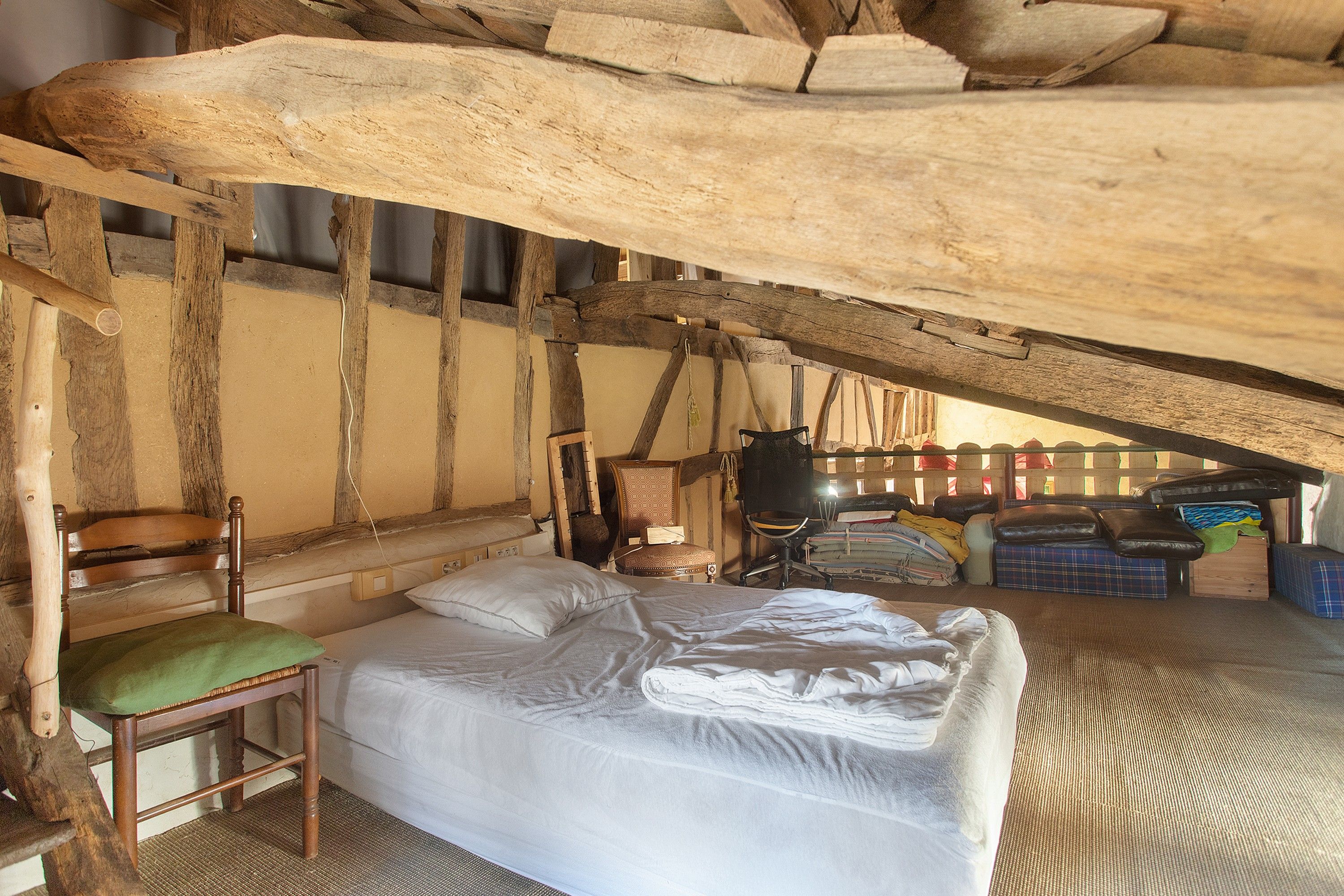 A rustic room with a bed, a chair, and a desk.