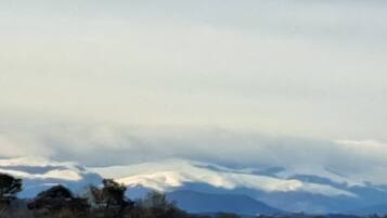 Een bergachtig landschap met besneeuwde toppen en een bewolkte lucht.