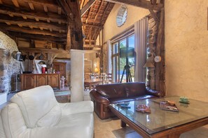 Um interior rústico com sofá de couro, mesa de centro de vidro e parede de pedra.